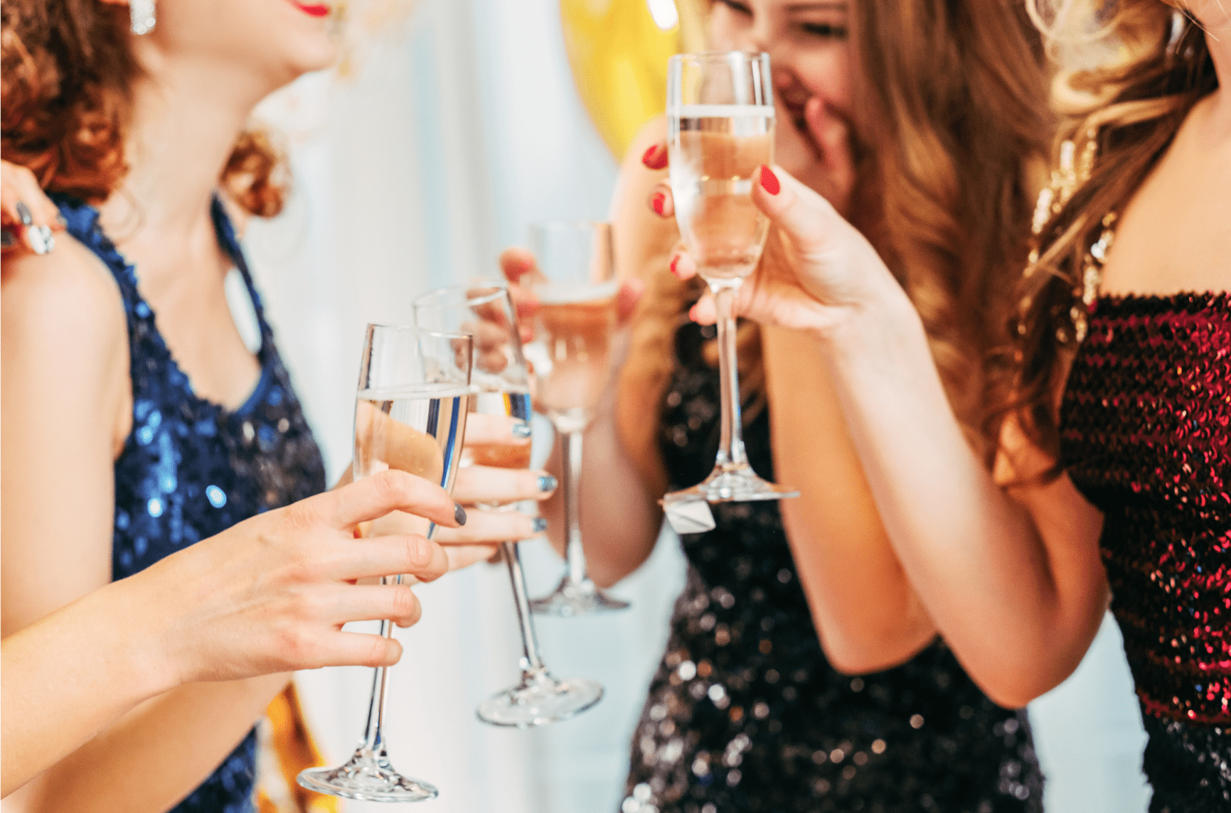 Young ladies drinking Champagne in cocktail dresses